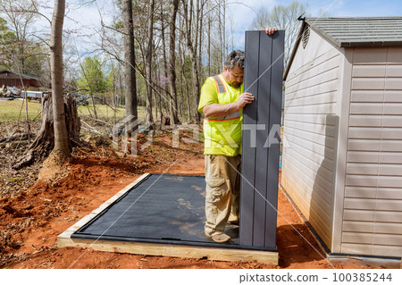 Job by worker assembling plastic shed for backyard near house Job by worker assembling plastic shed for backyard near house 100385244