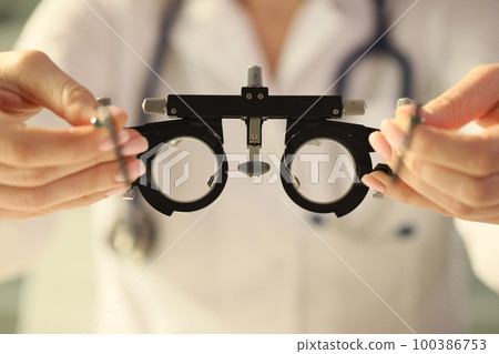 Ophthalmologist holds special ophthalmic glasses for checking vision close-up. 100386753