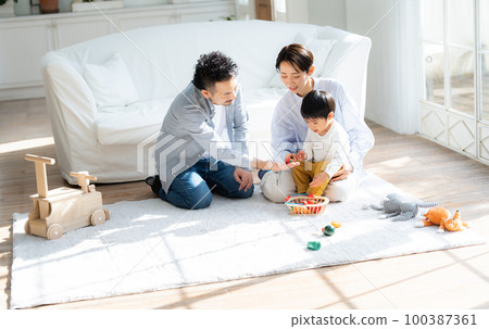 Family of three playing in the living room 100387361