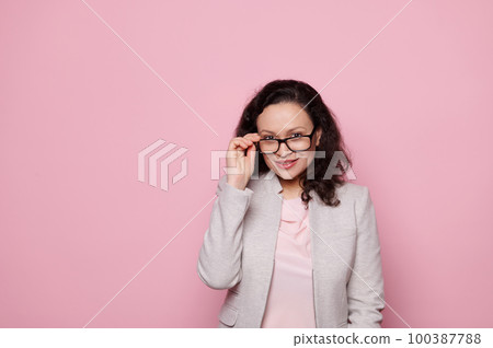 Beautiful dark-haired middle-aged woman in stylish elegant suit and spectacles, smiling looking at camera on isolated pink background. Eyesight. Health. Medicine. Ophthalmology and fashion concept 100387788