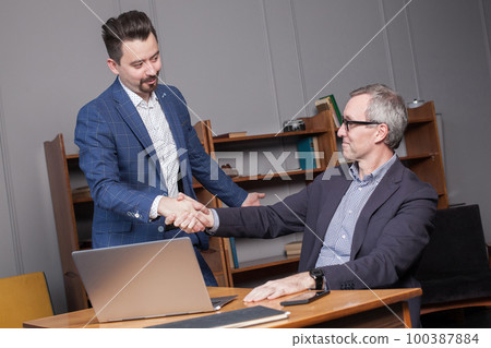 Senior happy businessman in suit with colleague making handshake in office 100387884