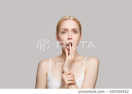 Surprised blonde woman touching her face isolated 100388482