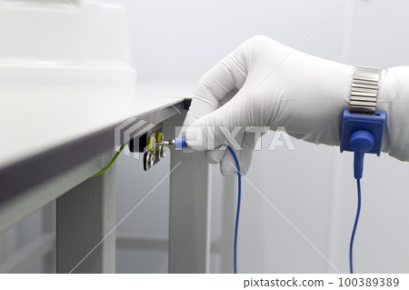 Bracelet on the hand of a man wearing ESD cloth and glove static resistance ESD bracelet or ground equipment, anti-static, used to safely ground is working. Semiconductor manufacturing. 100389389