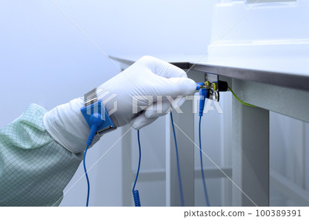 Bracelet on the hand of a man wearing ESD cloth and glove static resistance ESD bracelet or ground equipment, anti-static, used to safely ground is working. Semiconductor manufacturing. Bracelet on the hand of a man wearing ESD cloth and glove static resistance ESD bracelet or ground equipment, anti-static, used to safely ground is working. Semiconductor manufacturing. 100389391