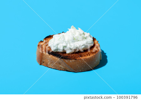 Tzatziki on toasted bread, isolated on a blue background Tzatziki on toasted bread, isolated on a blue background 100391796