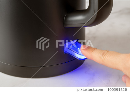 Woman finger turning on the switch to boil kettle. Woman finger turning on the switch to boil kettle. 100391826