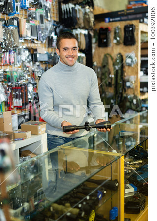 Seller man at counter in weapon shop Seller man at counter in weapon shop 100392006
