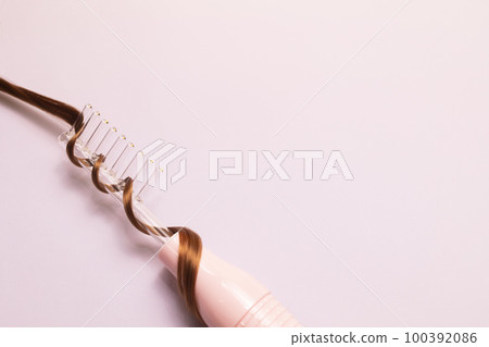 Flatly Darsonval Comb tube with brown hair strand on pink purple background. Cosmetic device, Beauty machine for face, eyes, hair, body care. Healthcare. Top view horizontal plane, copy space for text 100392086