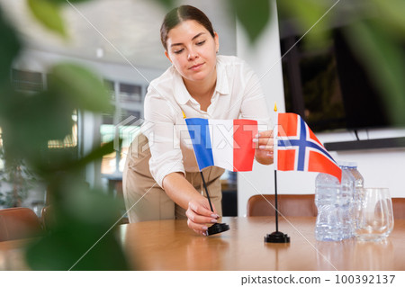 female assistant prepares a conference room for diplomats from Norway and France 100392137