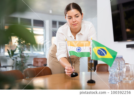 female assistant prepares conference room for diplomats of Brazil and India 100392256