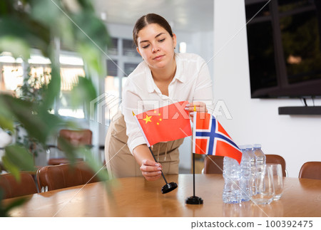 female assistant prepares a conference room for diplomats from Norway and China 100392475