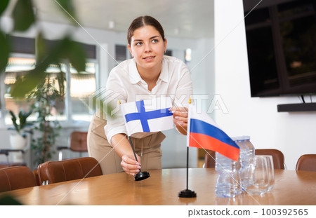 Young woman puts flags of Finland and Russia on table Young woman puts flags of Finland and Russia on table 100392565