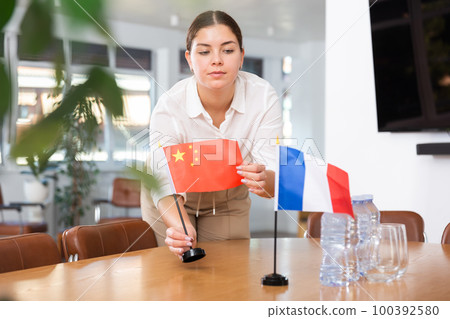 Young woman puts flags of China and France on table 100392580