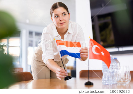 female assistant prepares conference room for diplomats of Turkey and Netherlands 100392623
