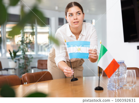 Young woman puts flags of Argentina and Italy on table Young woman puts flags of Argentina and Italy on table 100392631