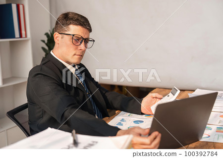 Portrait of business man working on analysis finance statistics and planning in a office. Make an account analysis report. real estate investment information financial and tax system concepts 100392784