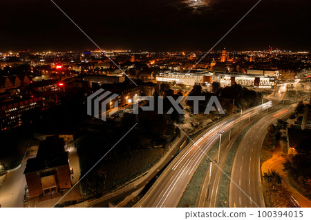 Top down view to road. Romantic night aerial photo of cars traveling. The light on the road at night in city. Background scenic road drone view. Tram railways  100394015