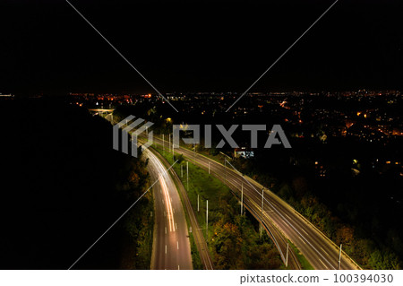 Top down view to road. Romantic night aerial photo of cars traveling. The light on the road at night in city. Background scenic road drone view. Tram railways  100394030