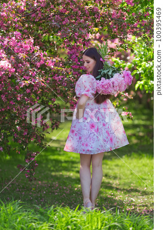 A girl , holding a bouquet of large pink peonies behind her back 100395469