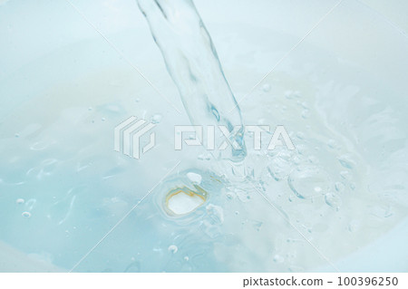 a jet of water pours into a container of water.  100396250