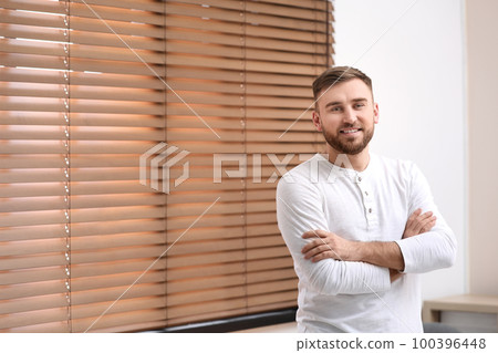 Handsome young man near window at home Handsome young man near window at home 100396448