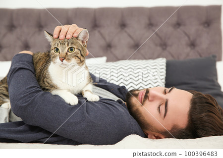 Happy man with cat on bed at home. Friendly pet Happy man with cat on bed at home. Friendly pet 100396483