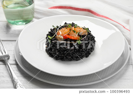 Delicious black risotto with seafood on white wooden table Delicious black risotto with seafood on white wooden table 100396493