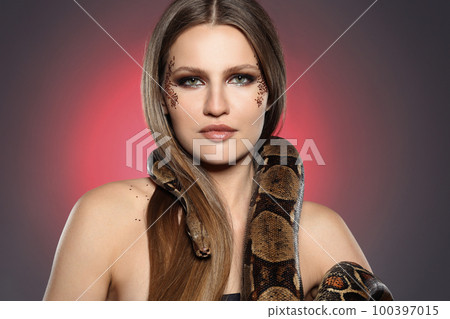 Beautiful woman with boa constrictor on color background 100397015
