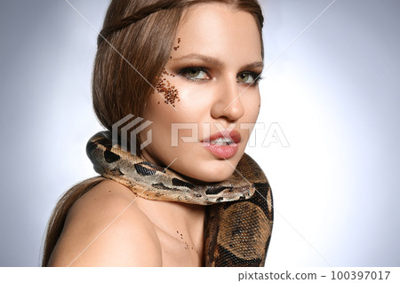 Beautiful woman with boa constrictor on light grey background, closeup 100397017