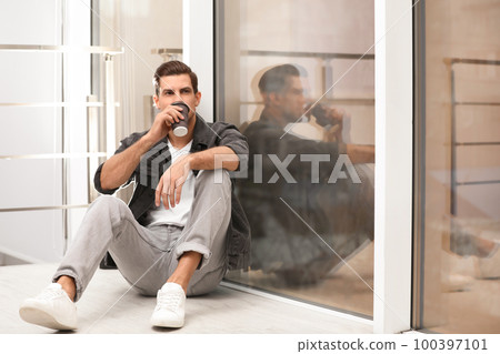 Handsome man drinking coffee near window at home Handsome man drinking coffee near window at home 100397101