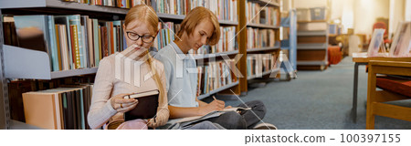 Friends student sit on floor near bookshelves in library and studying. Prepearing for exam 100397155