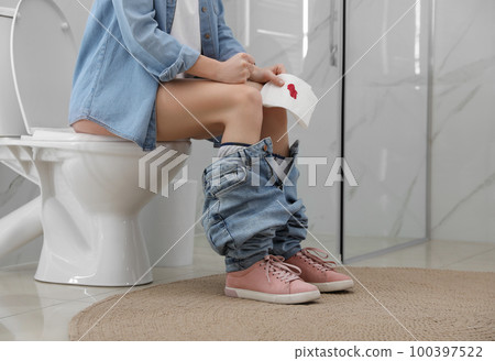 Woman holding toilet paper with blood stain in rest room, closeup. Hemorrhoid concept 100397522