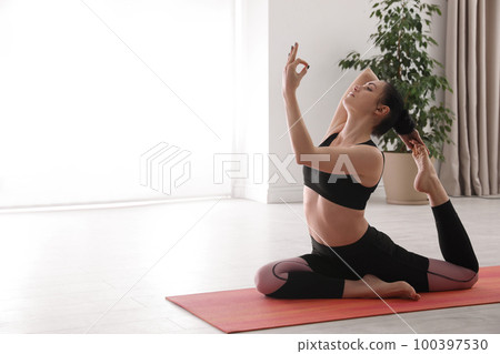 Woman practicing one legged king pigeon asana in yoga studio. Eka pada rajakapotasana pose 100397530