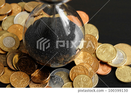 Time is money. Close up of hourglass with money coins 100399130