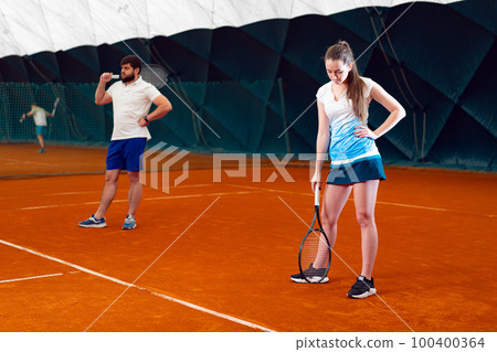 Pair of tennis players, man and woman waiting for service at indoor court Pair of tennis players, man and woman waiting for service at indoor court 100400364