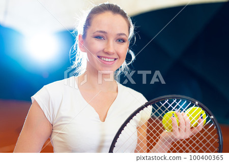 Close up portrait of a young attractive woman tennis player holding tennis racket 100400365