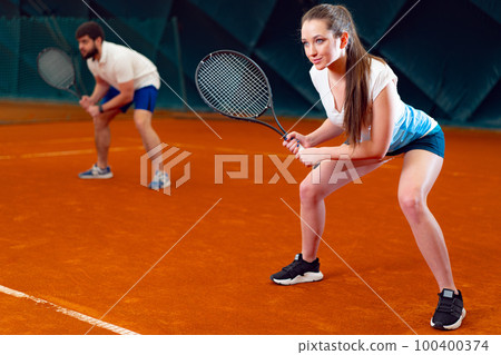 Pair of tennis players, man and woman waiting for service at indoor court Pair of tennis players, man and woman waiting for service at indoor court 100400374