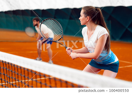 Pair of tennis players, man and woman waiting for service at indoor court Pair of tennis players, man and woman waiting for service at indoor court 100400550