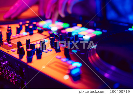 Close up of DJ hands on dj console mixer during concert in the club 100400719