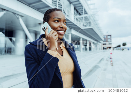 Beautiful young african woman using mobile phone in the street Beautiful young african woman using mobile phone in the street 100401012