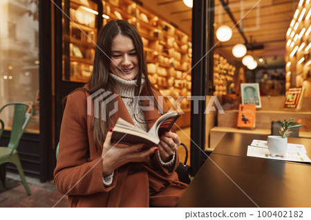 Portrait of beautiful young woman reading a book while relaxing in the cafe 100402182