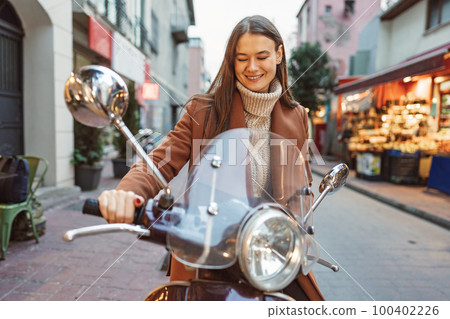 Portrait of attractive young cheerful woman riding moped scooter Portrait of attractive young cheerful woman riding moped scooter 100402226