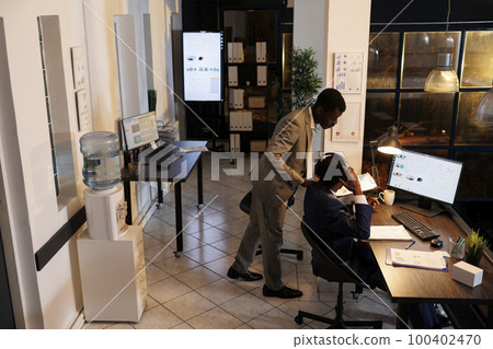 Businessmen analyzing marketing statistics report, discussing business strategy overtime in startup office. Executive manager explaining investment graph to worker, working at company profit 100402470