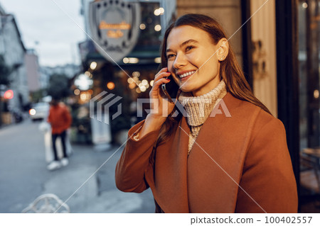 Young happy woman talking on the phone in the street 100402557