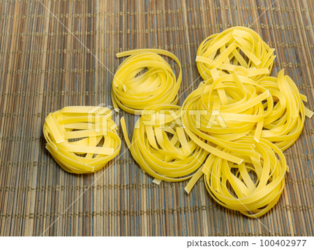 Pasta nests on a wicker background. Type of noodle. Culinary background. Cooking. Pasta nests on a wicker background. Type of noodle. Culinary background. Cooking. 100402977