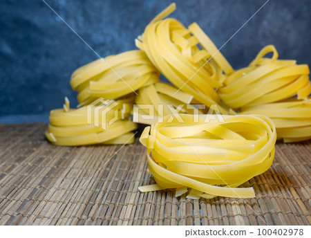 Pasta nests on a wicker background. Type of noodle. Culinary background. Cooking. Pasta nests on a wicker background. Type of noodle. Culinary background. Cooking. 100402978