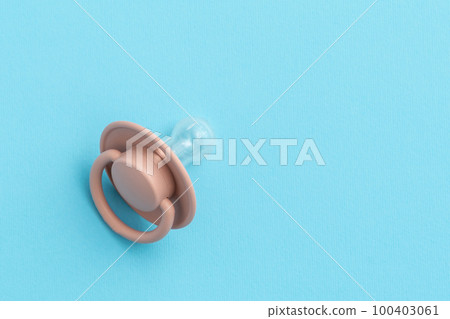 Pink baby pacifier on blue background with copy space, top view, flat lay. Newborn concept 100403061