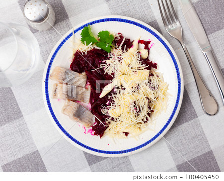 Pieces of chopped herring with beet and cheese served on plate 100405450