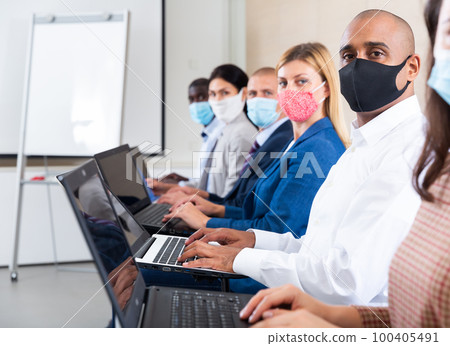 conference of international financial managers in mask with laptop in white room during quarantine 100405491