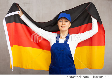 Cheerful female worker with wide grin on her face holding flag of germany 100405908